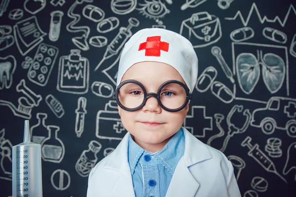 Mutlu küçük çocuk bir doktor desenli koyu arka plan üzerinde şırınga tutarak bardaklarda gibi