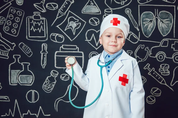 Niño feliz como médico sosteniendo el estetoscopio sobre fondo oscuro con patrón — Foto de Stock