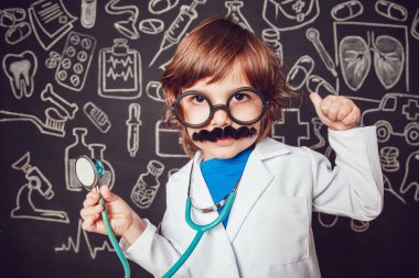 Doktor kostüm sthetoscope ve gösterileri sınıf desenli koyu arka plan üzerinde tutan küçük bir çocuk. Çocuk bıyıkları, gözlük vardır