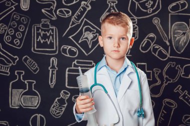 Küçük çocuk desenli koyu arka plan üzerinde şırınga tutarak doktor kostüm.