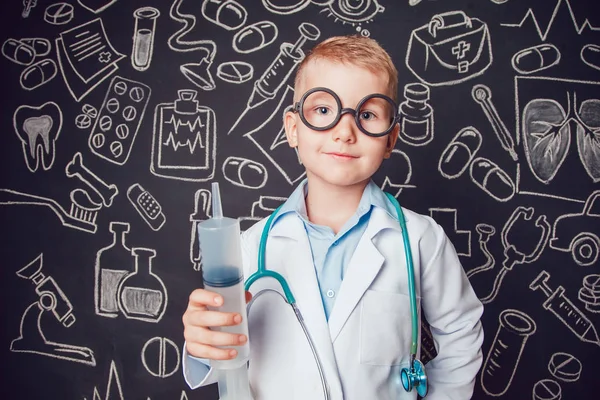 Mutlu küçük çocuk desenli koyu arka plan üzerinde şırınga tutarak doktor kostüm. Çocuk gözlük vardır
