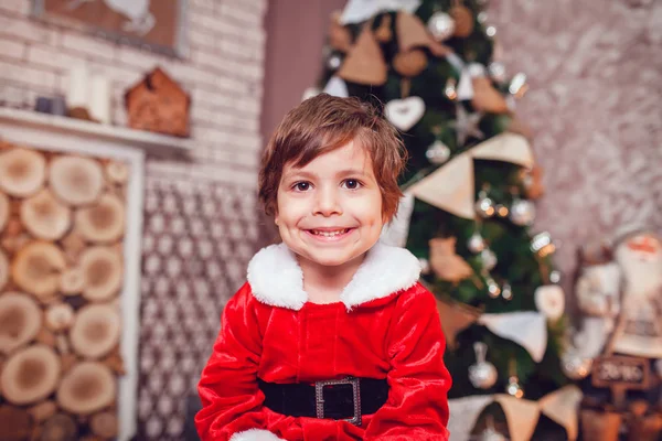 Petit garçon habillé en Père Noël assis dans la décoration de Noël. Nouvel An . — Photo