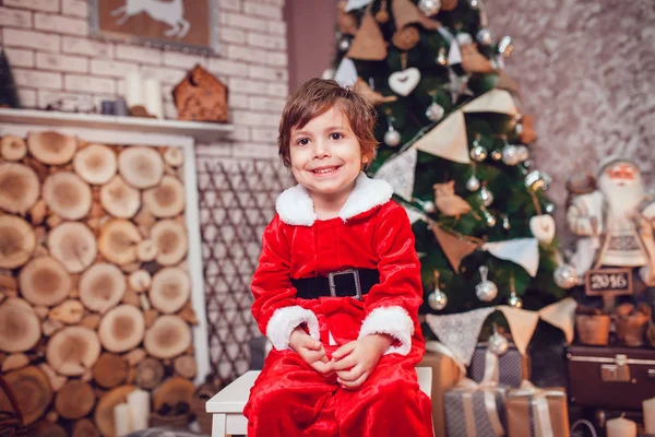 Petit garçon habillé en Père Noël assis dans la décoration de Noël. Nouvel An . — Photo