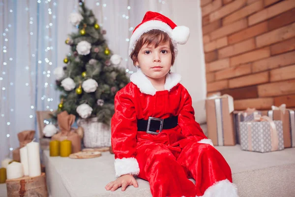 Kleine jongen verkleed als de Kerstman zitten in Kerstdecoratie. Nieuwjaar. — Stockfoto