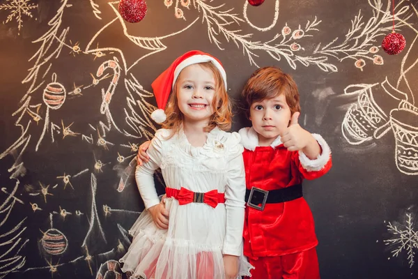 Enfants habillés en Père Noël debout sur fond sombre avec motif de Noël. Nouvel An . — Photo