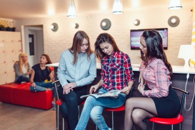 Hostel barda oturmuş, dergi ve konuşma tarama güzel kızlar.