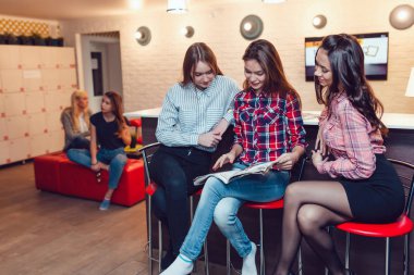 Hostel barda oturmuş, dergi ve konuşma tarama güzel kızlar.