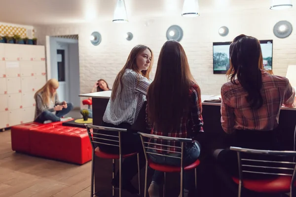 Gyönyörű lányok ülnek a bárban a Hostel, nézi a tv- és beszélgetés. — Stock Fotó