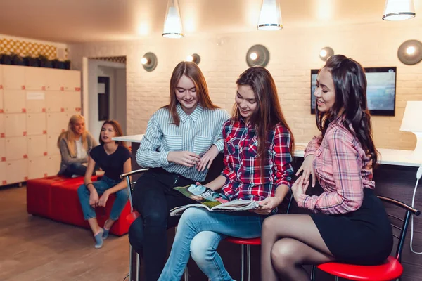 Gyönyörű lányok ülnek a bárban a Hostel, böngészés, magazinok és a beszéd. — Stock Fotó