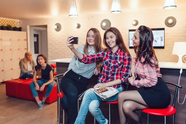 Gadis-gadis cantik duduk di bar di Hostel, browsing majalah, berbicara dan membuat selfie . — Stok Foto