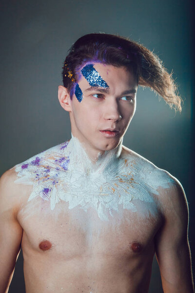 Fashion young man with creative face art and hair style on grey background.