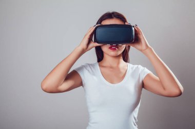 Sanal gerçeklik kullanan çekici kadın gri arka plan üzerinde koruyucu gözlük. VR kulaklık.