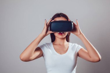 Sanal gerçeklik kullanan çekici kadın gri arka plan üzerinde koruyucu gözlük. VR kulaklık.
