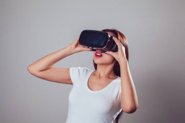 Sanal gerçeklik kullanan çekici kadın gri arka plan üzerinde koruyucu gözlük. VR kulaklık.