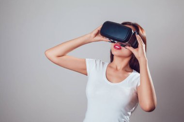 Sanal gerçeklik kullanan çekici kadın gri arka plan üzerinde koruyucu gözlük. VR kulaklık.