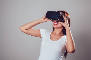 Sanal gerçeklik kullanan çekici kadın gri arka plan üzerinde koruyucu gözlük. VR kulaklık.