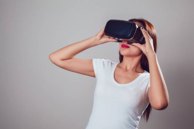 Sanal gerçeklik kullanan çekici kadın gri arka plan üzerinde koruyucu gözlük. VR kulaklık.