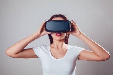 Sanal gerçeklik kullanan çekici kadın gri arka plan üzerinde koruyucu gözlük. VR kulaklık.