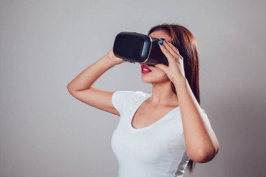 Sanal gerçeklik kullanan çekici kadın gri arka plan üzerinde koruyucu gözlük. VR kulaklık.