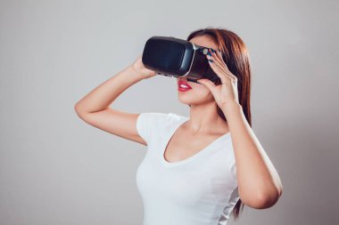 Sanal gerçeklik kullanan çekici kadın gri arka plan üzerinde koruyucu gözlük. VR kulaklık.