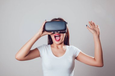 Sanal gerçeklik kullanan çekici ve mutlu kadın gri arka plan üzerinde koruyucu gözlük. VR kulaklık.