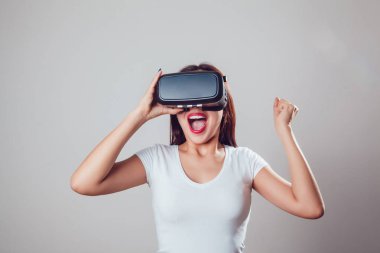 Sanal gerçeklik kullanan çekici ve mutlu kadın gri arka plan üzerinde koruyucu gözlük. VR kulaklık.