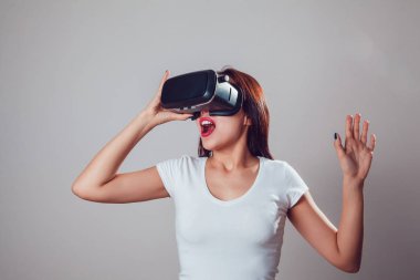 Sanal gerçeklik kullanan çekici ve mutlu kadın gri arka plan üzerinde koruyucu gözlük. VR kulaklık.