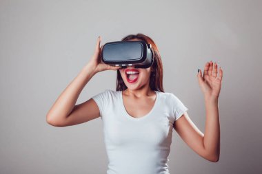 Sanal gerçeklik kullanan çekici ve mutlu kadın gri arka plan üzerinde koruyucu gözlük. VR kulaklık.