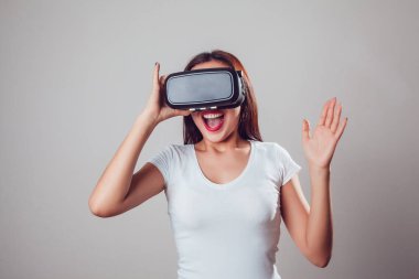 Sanal gerçeklik kullanan çekici ve mutlu kadın gri arka plan üzerinde koruyucu gözlük. VR kulaklık.