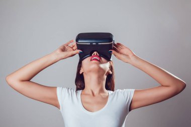 Sanal gerçeklik kullanan çekici kadın gri arka plan üzerinde koruyucu gözlük. VR kulaklık.
