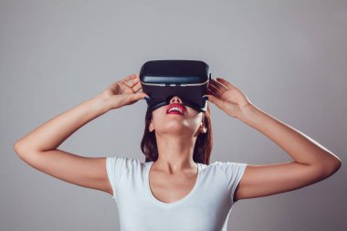 Sanal gerçeklik kullanan çekici kadın gri arka plan üzerinde koruyucu gözlük. VR kulaklık.