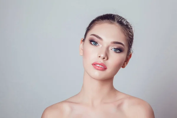 Hermosa chica morena con maquillaje sobre fondo gris, la juventud y el cuidado de la piel concepto . — Foto de Stock