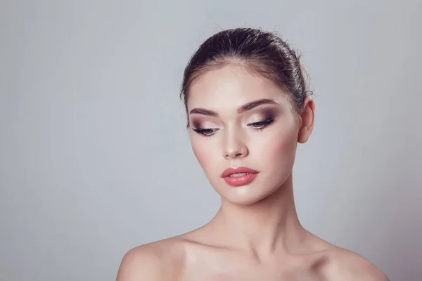 Schöne brünette Mädchen mit Make-up auf grauem Hintergrund, Jugend und Hautpflege-Konzept. — Stockfoto