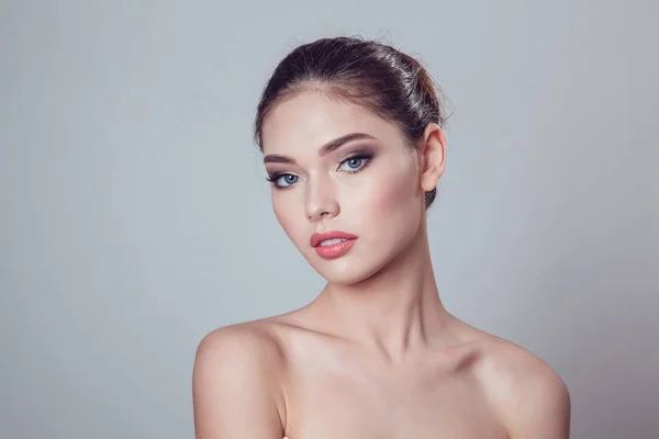 Güzel esmer kız makyaj gri arka plan üzerinde ile gençlik ve cilt bakım kavramı.