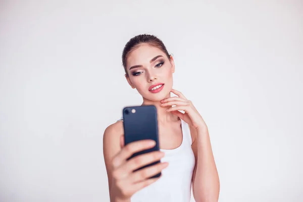 Hermosa chica morena con maquillaje hacer selfie sobre fondo blanco . —  Fotos de Stock