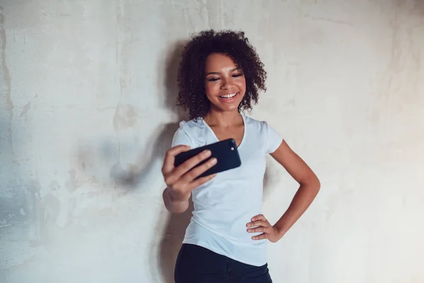 Mooie lachende Afrikaanse meisje maken selfie op grijze achtergrond — Stockfoto