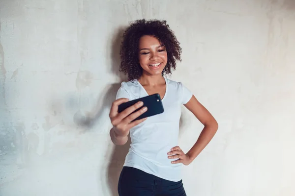 Mooie lachende Afrikaanse meisje maken selfie op grijze achtergrond — Stockfoto