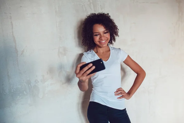 Mooie lachende Afrikaanse meisje maken selfie op grijze achtergrond — Stockfoto