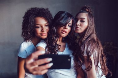 Üç beautyful gülümseyen kız beyaz t-shirt, Face ve selfie smartphone kullanarak yapmak.