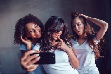 Üç beautyful gülümseyen kız beyaz t-shirt, Face ve selfie smartphone kullanarak yapmak.