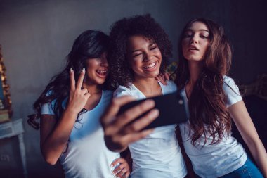Üç beautyful gülümseyen kız beyaz t-shirt, Face ve selfie smartphone kullanarak yapmak.