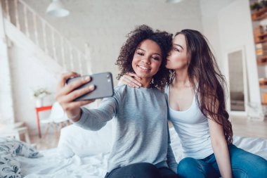 Güzel kızlar yatakta evde oturan selfie olun.