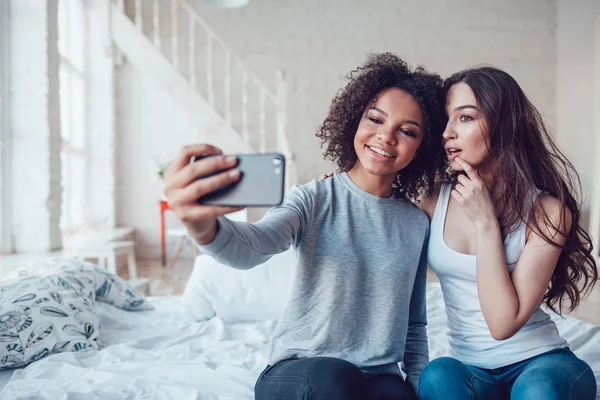 Hermosas chicas hacen selfie sentado en la cama en casa . —  Fotos de Stock