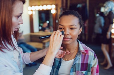 Profesyonel makyaj güzellik stüdyosu içinde genç Afrikalı kadın sanatçı makyaj