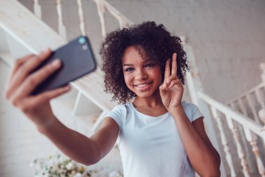 Beyaz t-shirt Beautyful Afrikalı kız olun smartphone evde kullanma selfie.