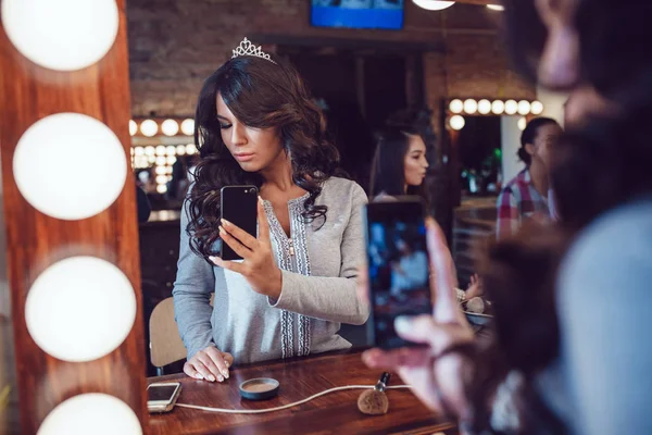 Красива жінка після макіяжу дивиться у дзеркало і робить селфі в студії краси . — стокове фото