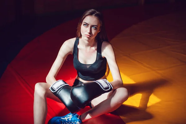 Ragazza sportiva con i guanti da boxe che si appoggia sulla formazione nella palestra vecchio stile . — Foto Stock