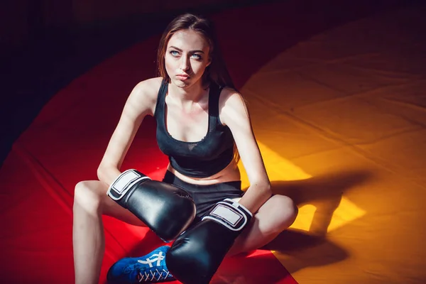 Спортивная девушка в боксёрских перчатках отдыхает на тренировках в тренажерном зале старого стиля . — стоковое фото