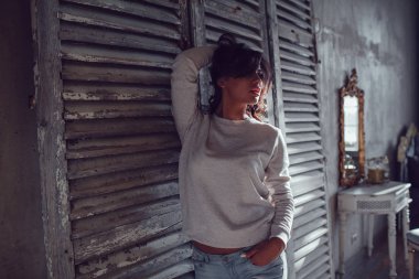 Güzel genç womanl ahşap duvar arka plan üzerinde duran boş Kazak giymiş. Mock-up.