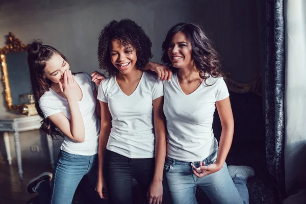 Hermosas chicas sonrientes divirtiéndose en camisas blancas en la cama. Camiseta maqueta . — Foto de Stock